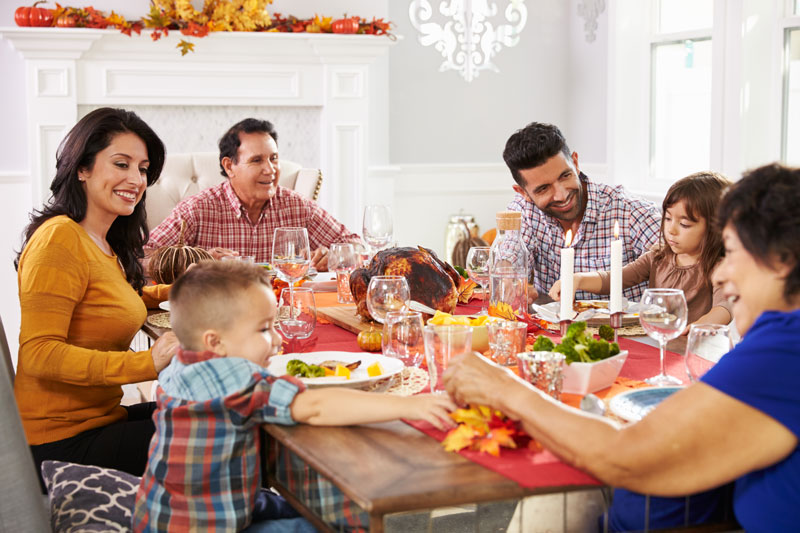 a family sitting around a table eating thanksgiving dinner